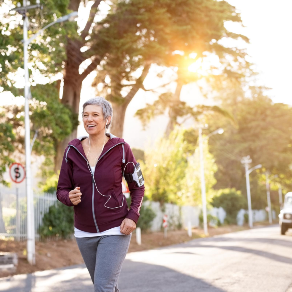 woman with gray pixie cut and maroon hoodie jogs down a street
