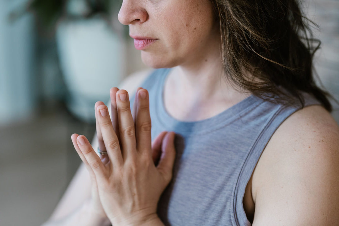 white woman cropped from nose to chest with prayer hands at heart