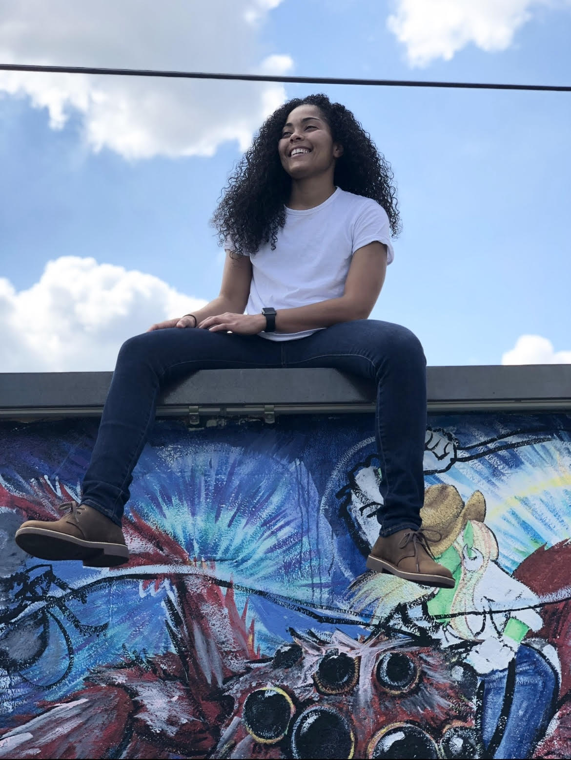 photo of Kristal Lollis sitting on a graffitied wall