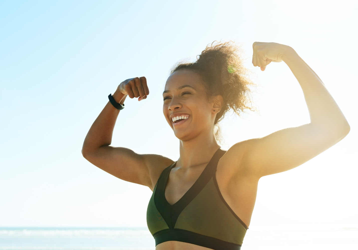 Black woman in a sports bra flexing her biceps