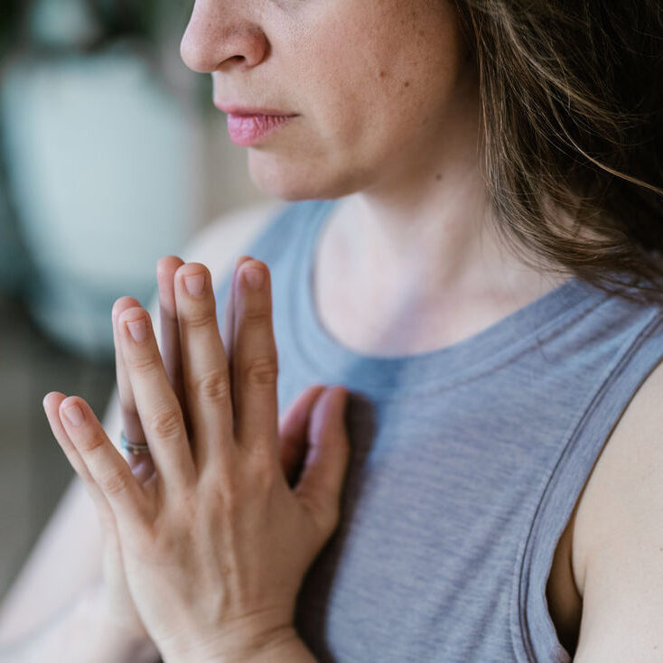 white woman cropped from nose to chest with prayer hands at heart