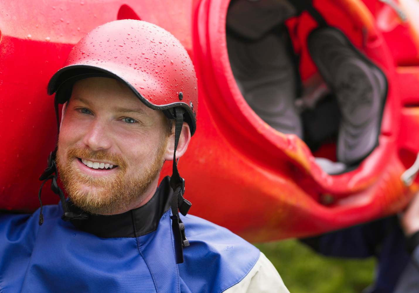 white man with a beard carries a kayak